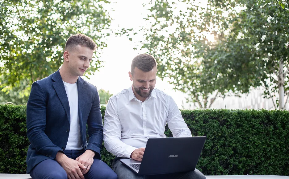 Filip i Jakub pracują przy laptopie w plenerze